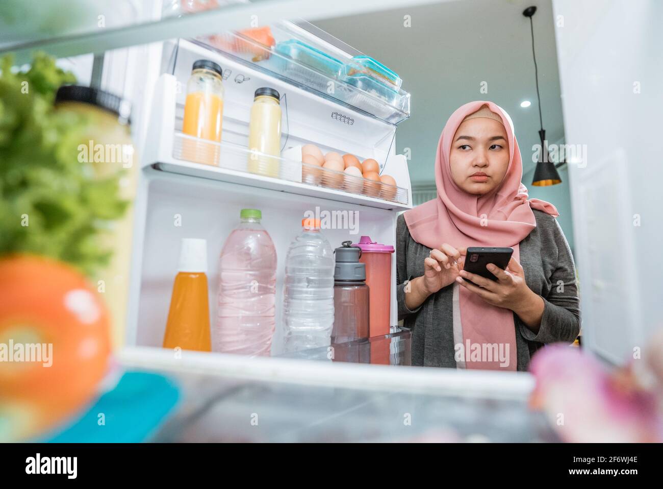 Woman Using Her Smartphone To Buy Groceries While Open Her Fridge Stock Photo Image Of Food